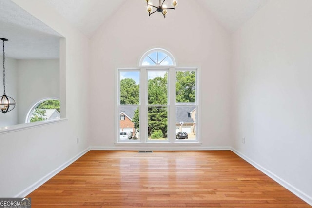 interior space with a chandelier, light hardwood / wood-style flooring, a textured ceiling, and high vaulted ceiling