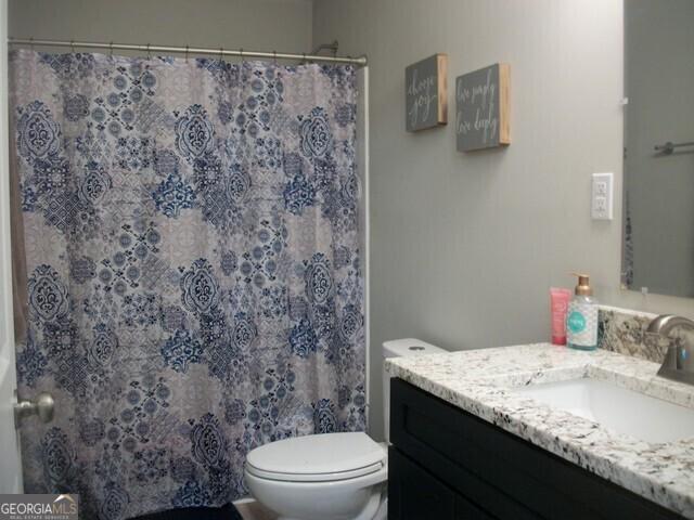 bathroom featuring vanity, curtained shower, and toilet