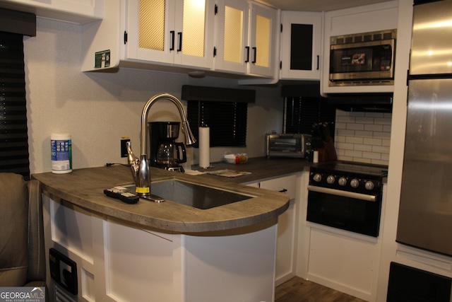 kitchen with tasteful backsplash, dark hardwood / wood-style flooring, white cabinetry, sink, and stainless steel appliances