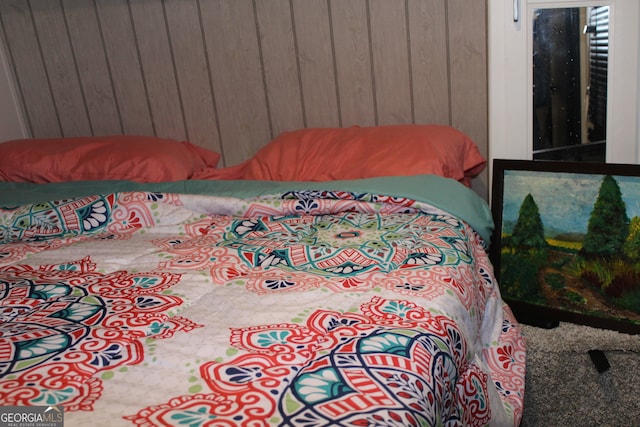 carpeted bedroom with wood walls