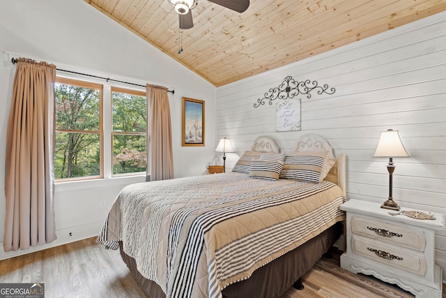 bedroom featuring wood walls, wood ceiling, vaulted ceiling, ceiling fan, and light hardwood / wood-style flooring