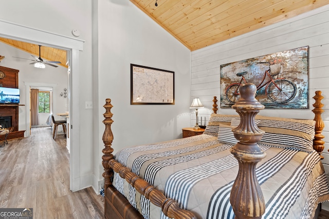 bedroom featuring high vaulted ceiling, wood ceiling, wooden walls, and light hardwood / wood-style floors