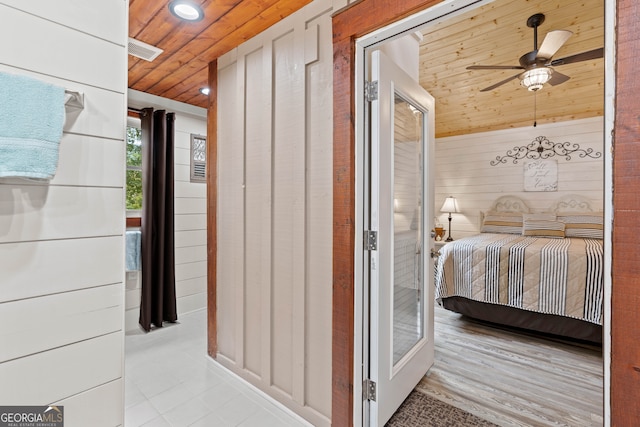 bedroom with wood walls, light tile patterned flooring, ceiling fan, and wood ceiling