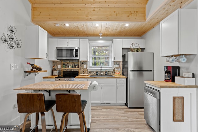 kitchen with wood counters, white cabinetry, sink, and appliances with stainless steel finishes