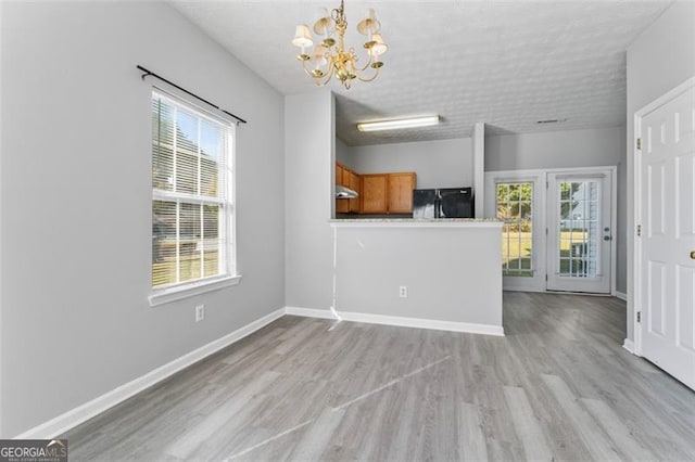 interior space with a notable chandelier, a textured ceiling, and light wood-type flooring