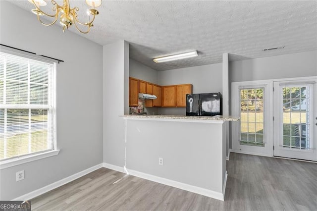 kitchen featuring light hardwood / wood-style floors, kitchen peninsula, a textured ceiling, and black refrigerator