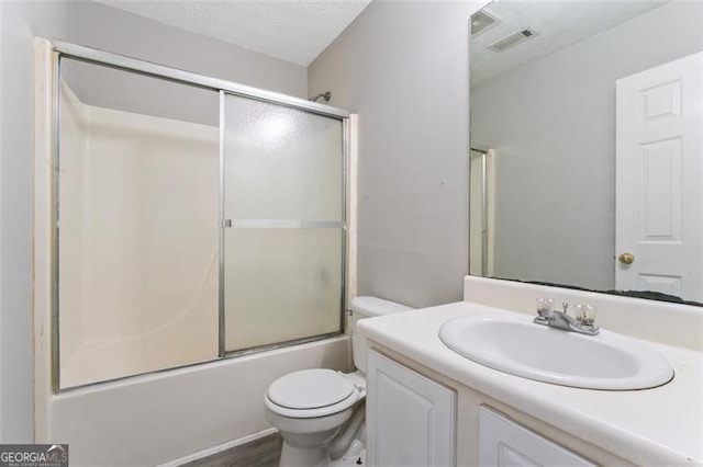 full bathroom featuring toilet, wood-type flooring, bath / shower combo with glass door, vanity, and a textured ceiling