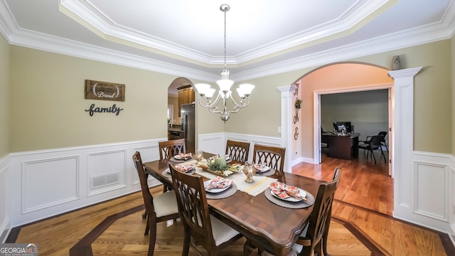 dining area featuring hardwood / wood-style flooring, ornamental molding, and a raised ceiling