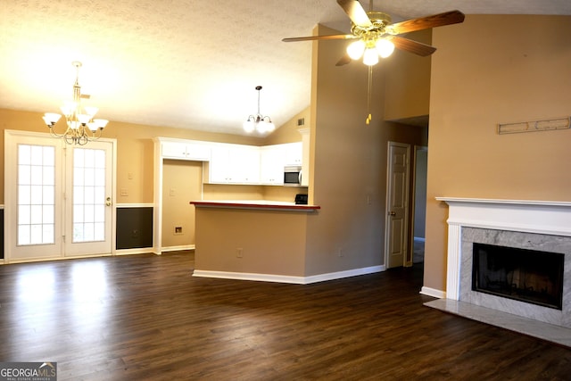 unfurnished living room featuring high vaulted ceiling, dark hardwood / wood-style floors, ceiling fan with notable chandelier, and a high end fireplace