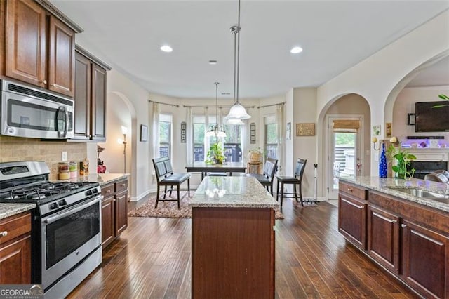 kitchen featuring stainless steel appliances, dark wood-type flooring, pendant lighting, and a kitchen island