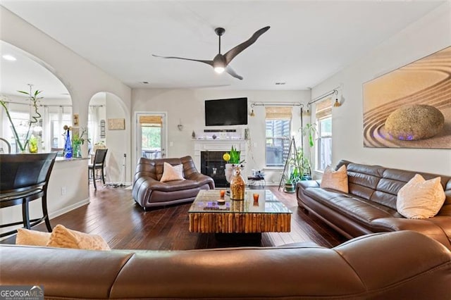 living room featuring ceiling fan, dark hardwood / wood-style floors, and plenty of natural light