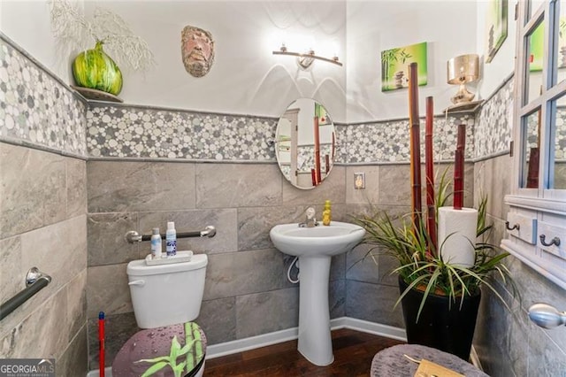 bathroom with toilet, hardwood / wood-style flooring, sink, and tile walls