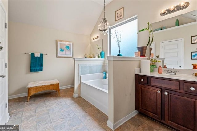 bathroom featuring a bath, a notable chandelier, vaulted ceiling, and vanity