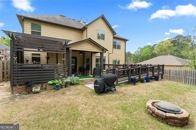 rear view of property with a pergola, an outdoor fire pit, and a lawn