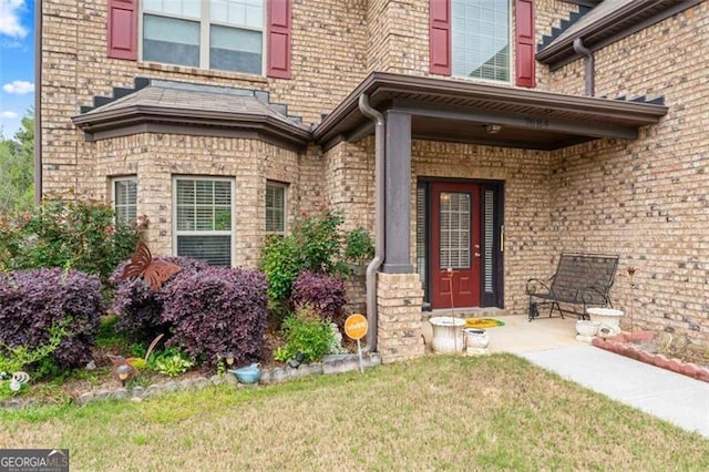 view of exterior entry featuring a lawn