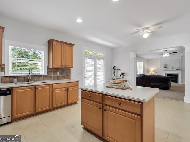 kitchen featuring stainless steel dishwasher, a center island, decorative columns, backsplash, and sink