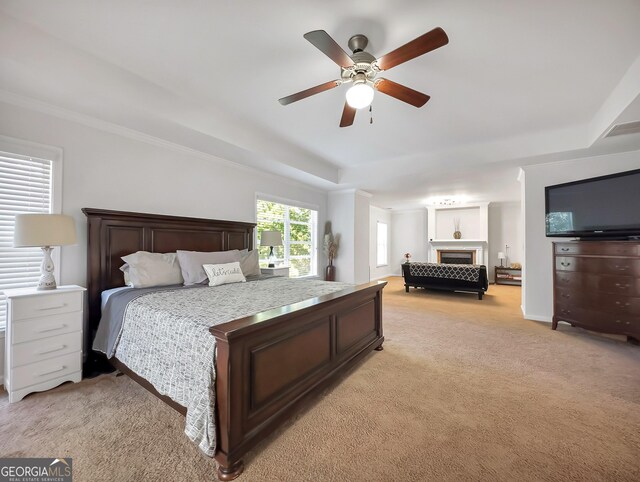 carpeted bedroom with ceiling fan, a tray ceiling, and crown molding