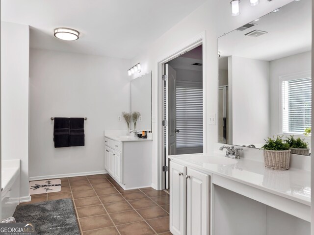 bathroom with a tub, vanity, and tile patterned flooring