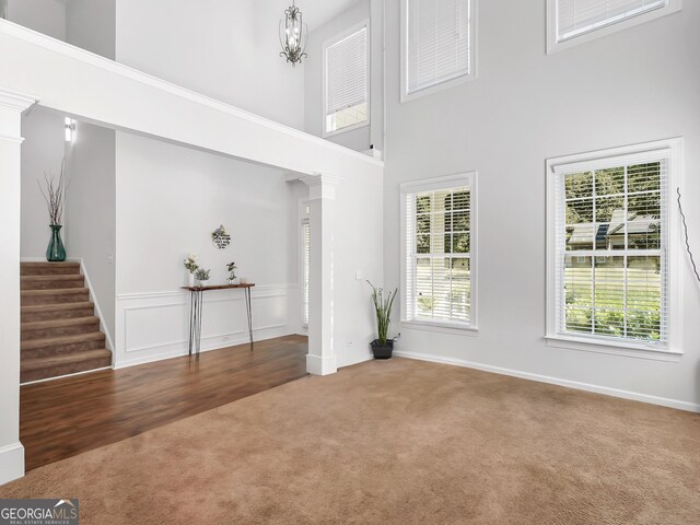 carpeted entrance foyer featuring a towering ceiling and decorative columns