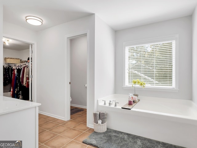 bathroom with a washtub, tile patterned flooring, and vanity