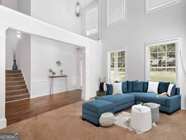 living room featuring carpet floors, a wealth of natural light, ornate columns, and a towering ceiling