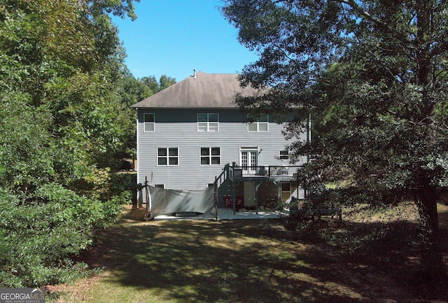 back of property with a yard, a patio, and a wooden deck