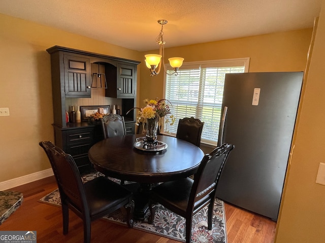 dining space with light hardwood / wood-style flooring, a textured ceiling, and a notable chandelier