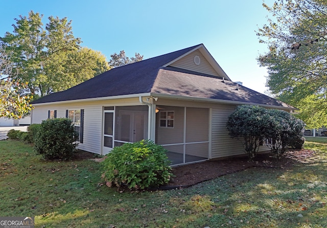 back of property with a sunroom and a lawn