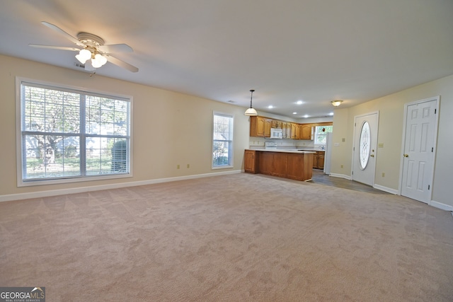 unfurnished living room featuring light carpet and ceiling fan