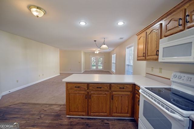 kitchen with hanging light fixtures, kitchen peninsula, white appliances, and dark hardwood / wood-style flooring