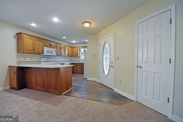 kitchen with kitchen peninsula, carpet flooring, and white appliances