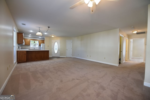 unfurnished living room with light carpet, sink, and ceiling fan