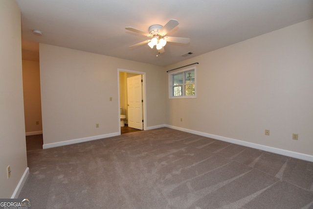 spare room featuring dark colored carpet and ceiling fan