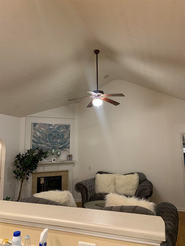 living room with lofted ceiling, a tiled fireplace, wood-type flooring, and ceiling fan