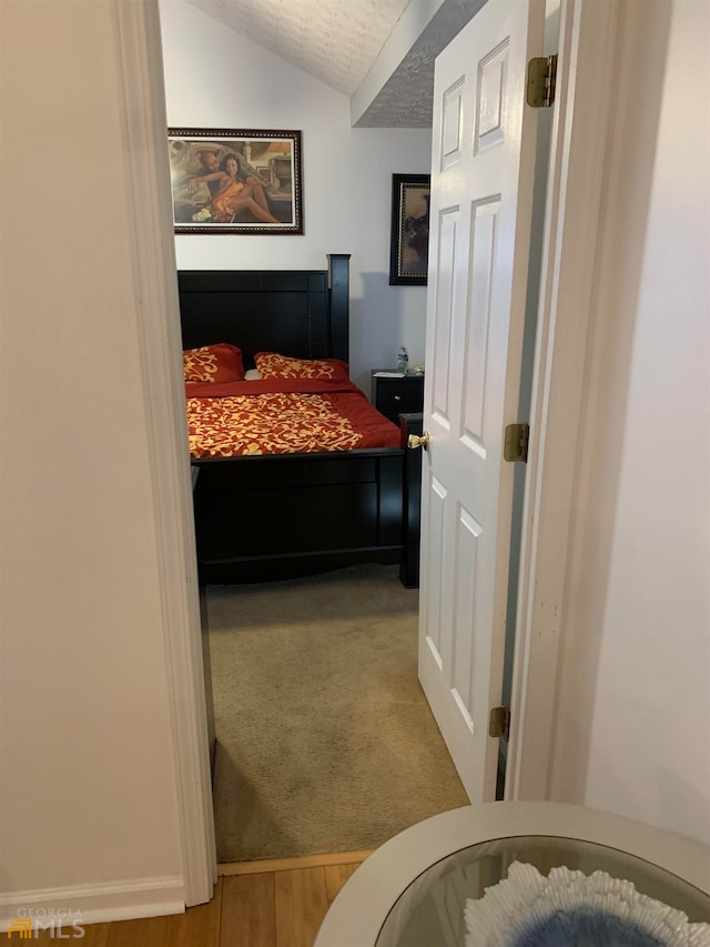 bedroom featuring a textured ceiling, carpet flooring, and vaulted ceiling