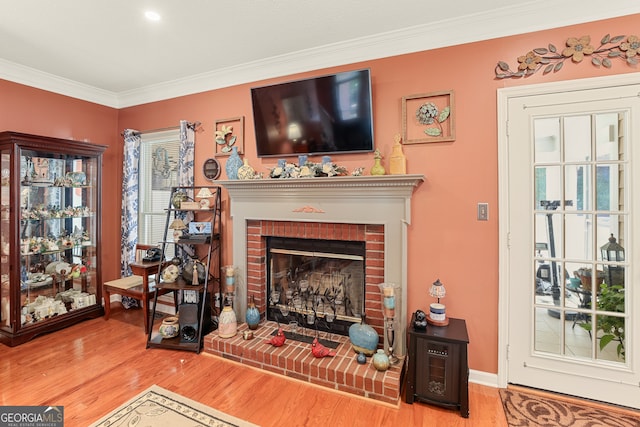 sitting room with crown molding, hardwood / wood-style flooring, and a brick fireplace