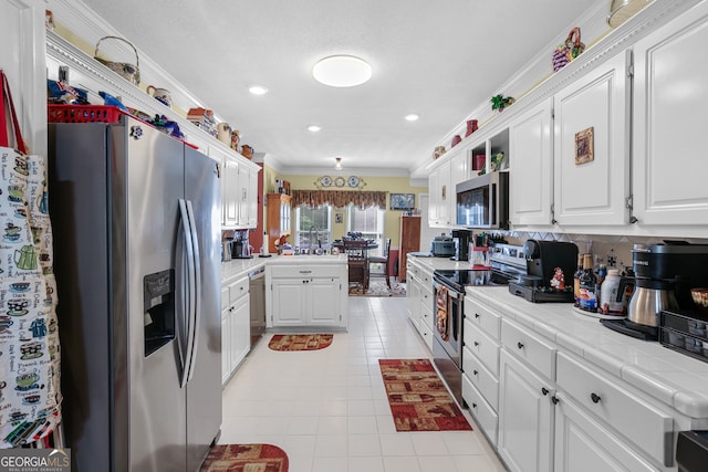 kitchen with tile countertops, decorative backsplash, stainless steel appliances, white cabinets, and ornamental molding