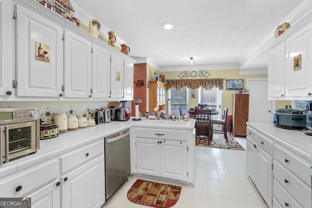 kitchen featuring white cabinetry, tile countertops, and stainless steel dishwasher