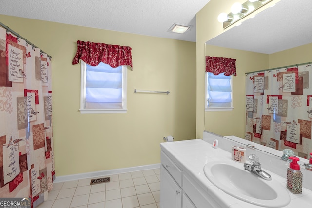 bathroom featuring vanity, a textured ceiling, tile patterned floors, and a wealth of natural light