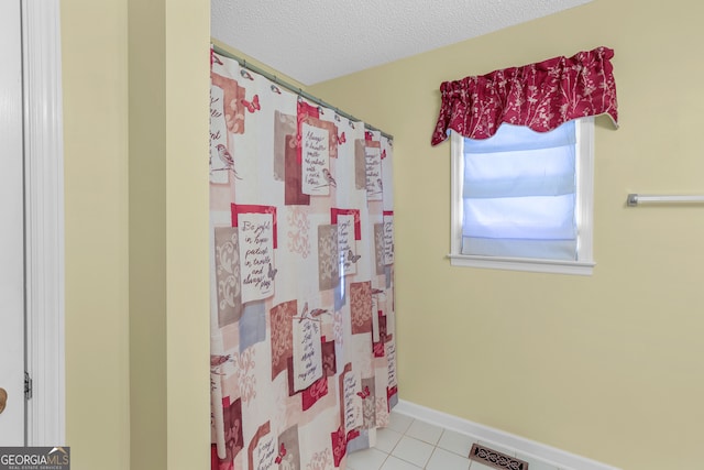 bathroom with curtained shower, a textured ceiling, and tile patterned flooring