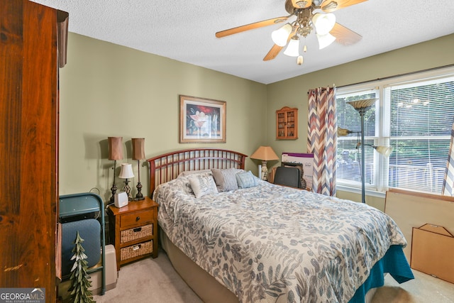 bedroom featuring a textured ceiling, light colored carpet, and ceiling fan