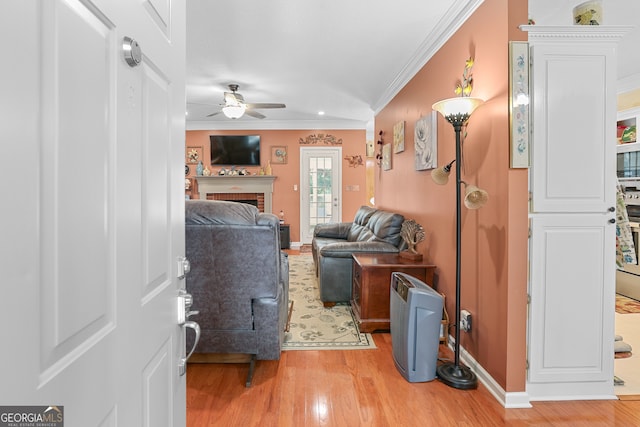 living room featuring light hardwood / wood-style floors, crown molding, a brick fireplace, and ceiling fan