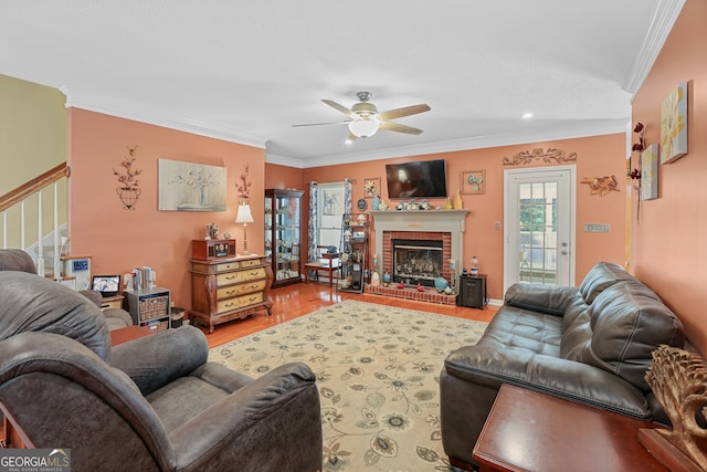 living room with ornamental molding, a fireplace, wood-type flooring, and ceiling fan