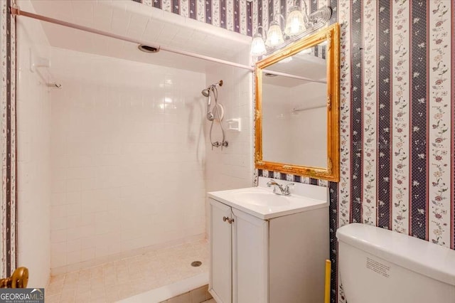 bathroom featuring vanity, toilet, and tiled shower