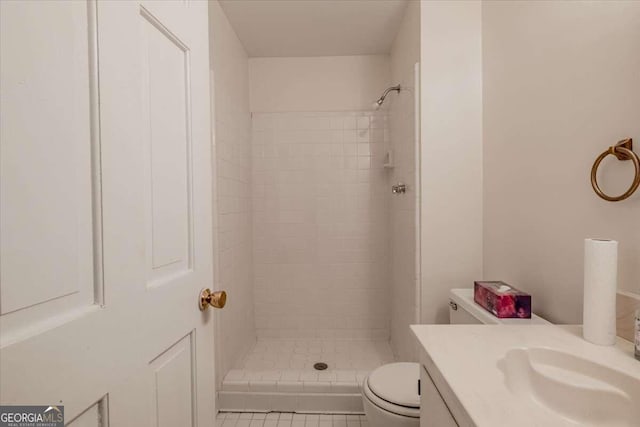 bathroom featuring vanity, tiled shower, toilet, and tile patterned floors