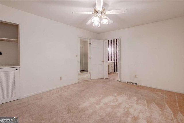 unfurnished bedroom with connected bathroom, light colored carpet, and ceiling fan