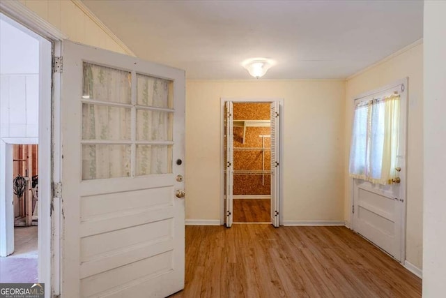 doorway with light hardwood / wood-style floors and crown molding