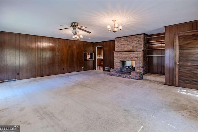 unfurnished living room featuring ceiling fan, a fireplace, light colored carpet, and wood walls