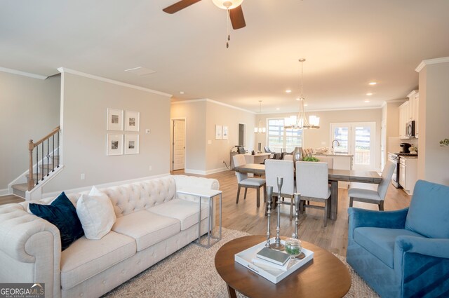 living room with light hardwood / wood-style flooring, ceiling fan with notable chandelier, and crown molding