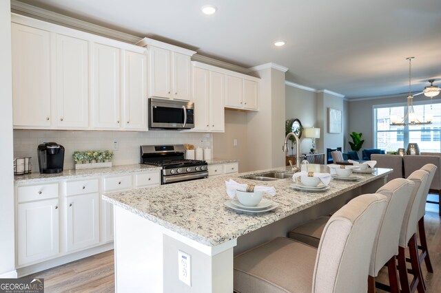 kitchen featuring sink, appliances with stainless steel finishes, white cabinetry, and an island with sink